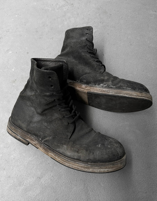 Pair of worn black boots on a gray concrete surface