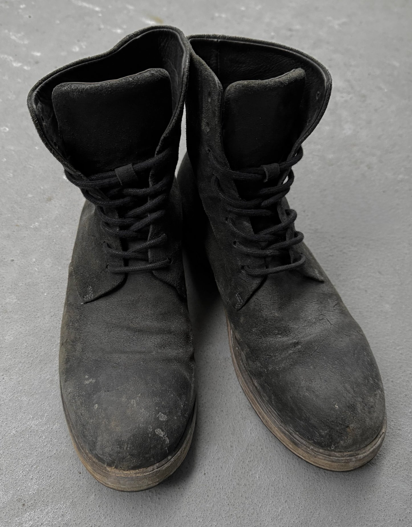 Pair of black leather boots on a gray concrete surface