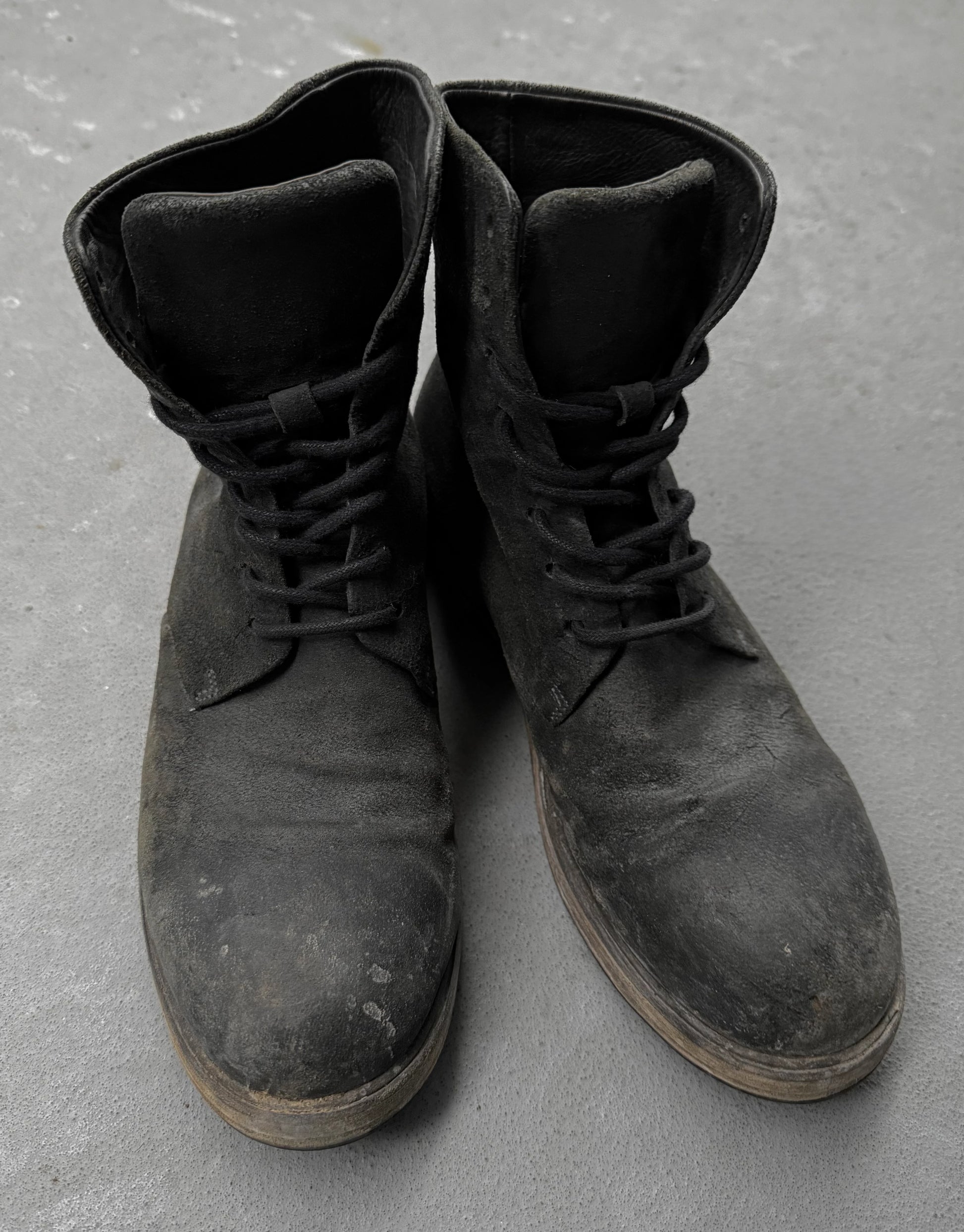 Pair of black leather boots on a gray concrete surface