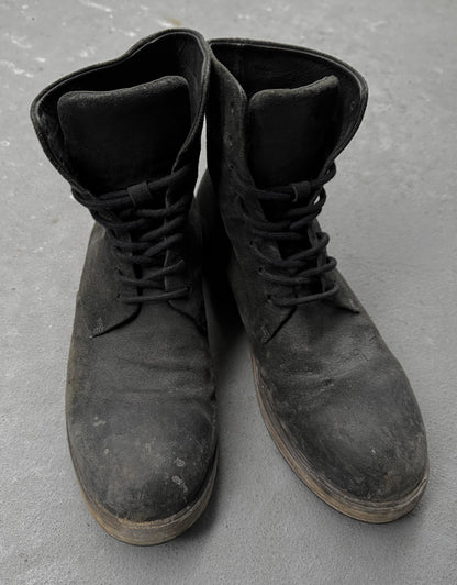Pair of black leather boots on a gray concrete surface