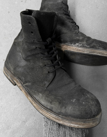 Pair of worn black leather boots on a light gray background