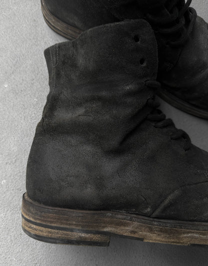 Close-up of black suede boots on a gray concrete surface
