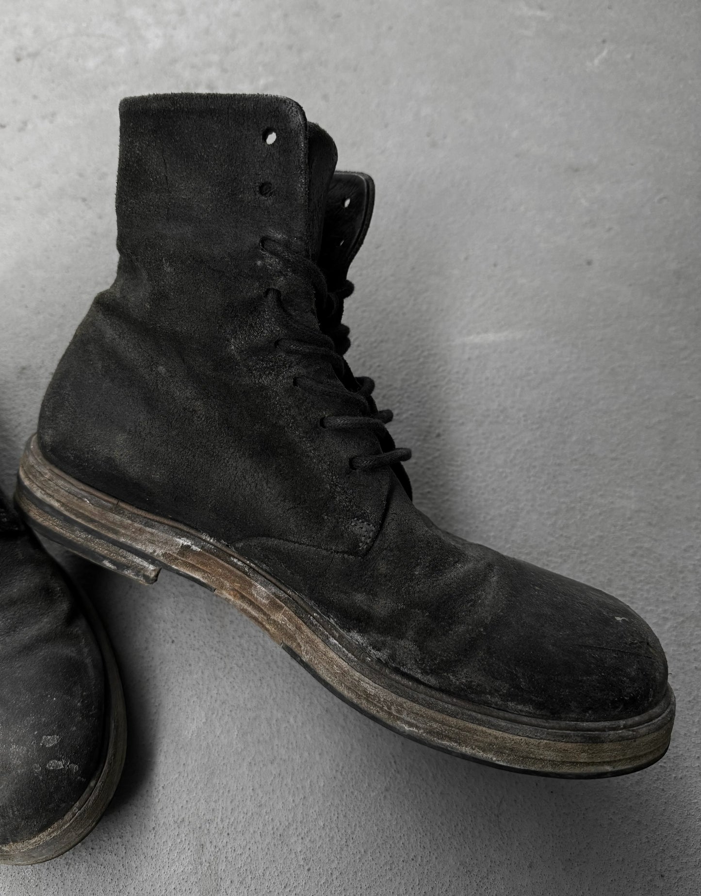 Pair of black leather boots on a gray surface