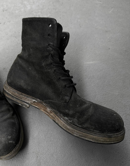 Pair of black leather boots on a gray surface