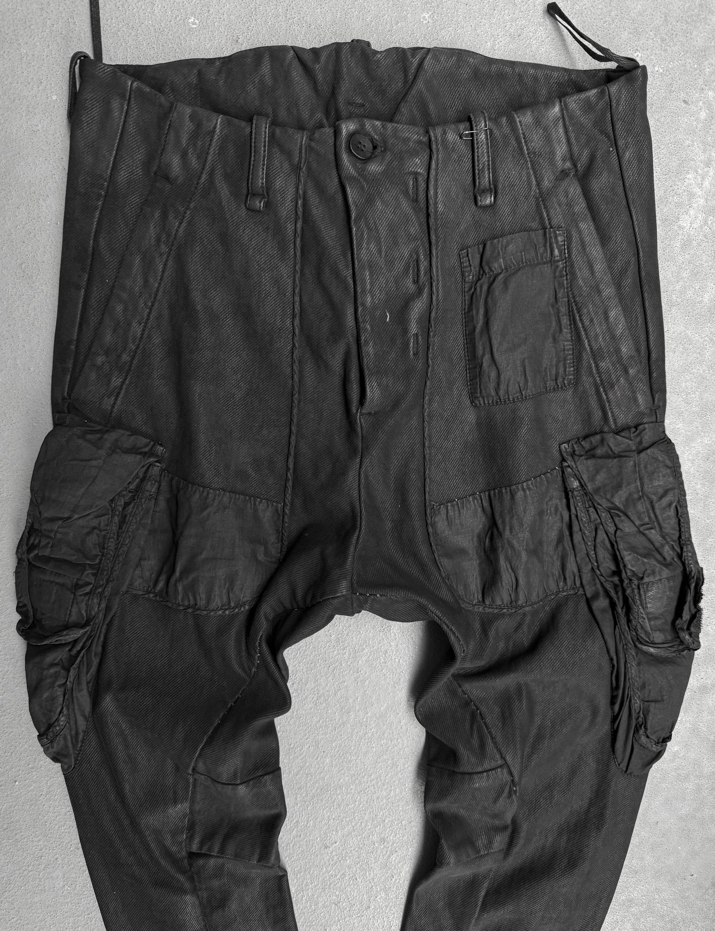 Black cargo pants hanging against a light gray background