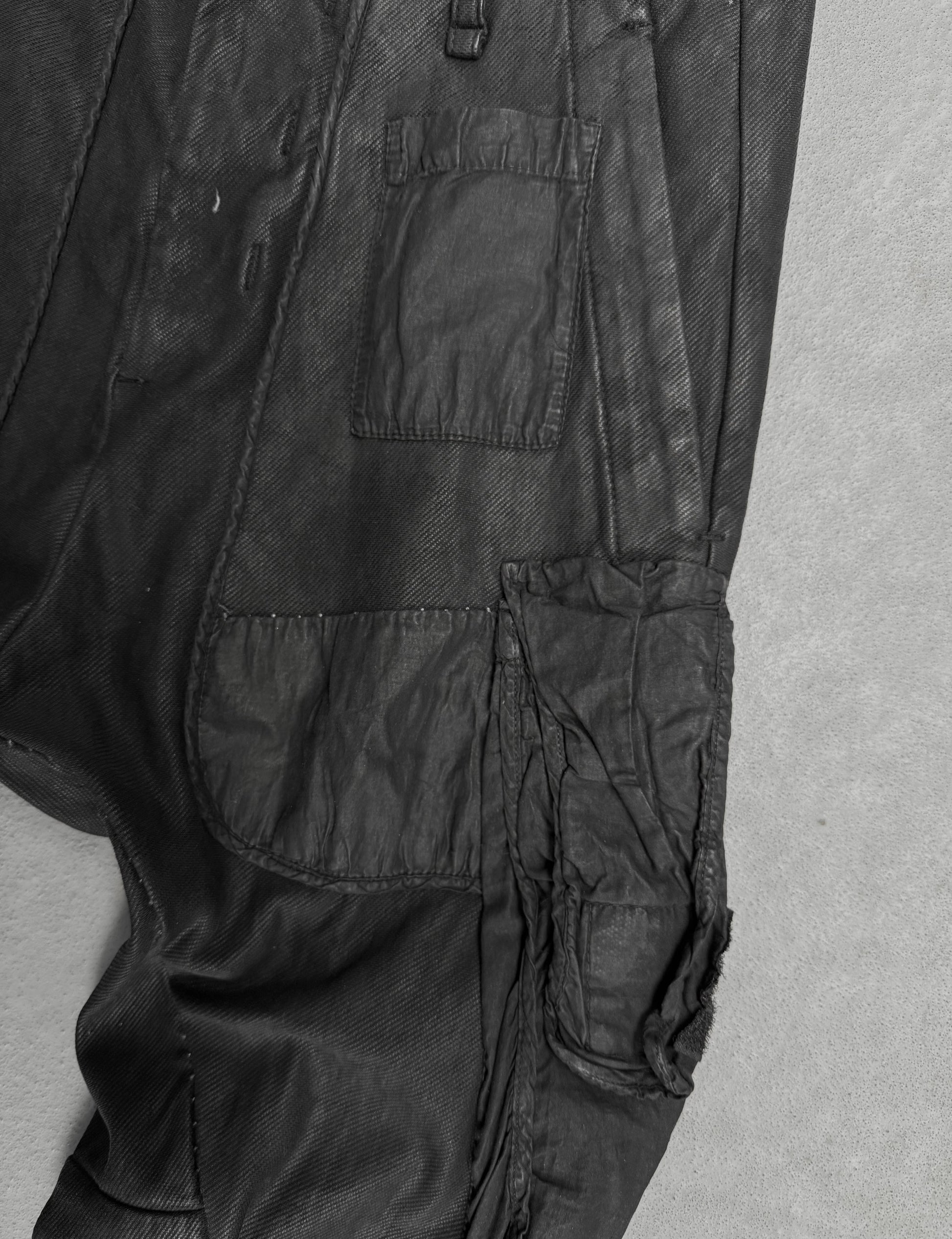 Close-up of black pants with multiple pockets on a gray background