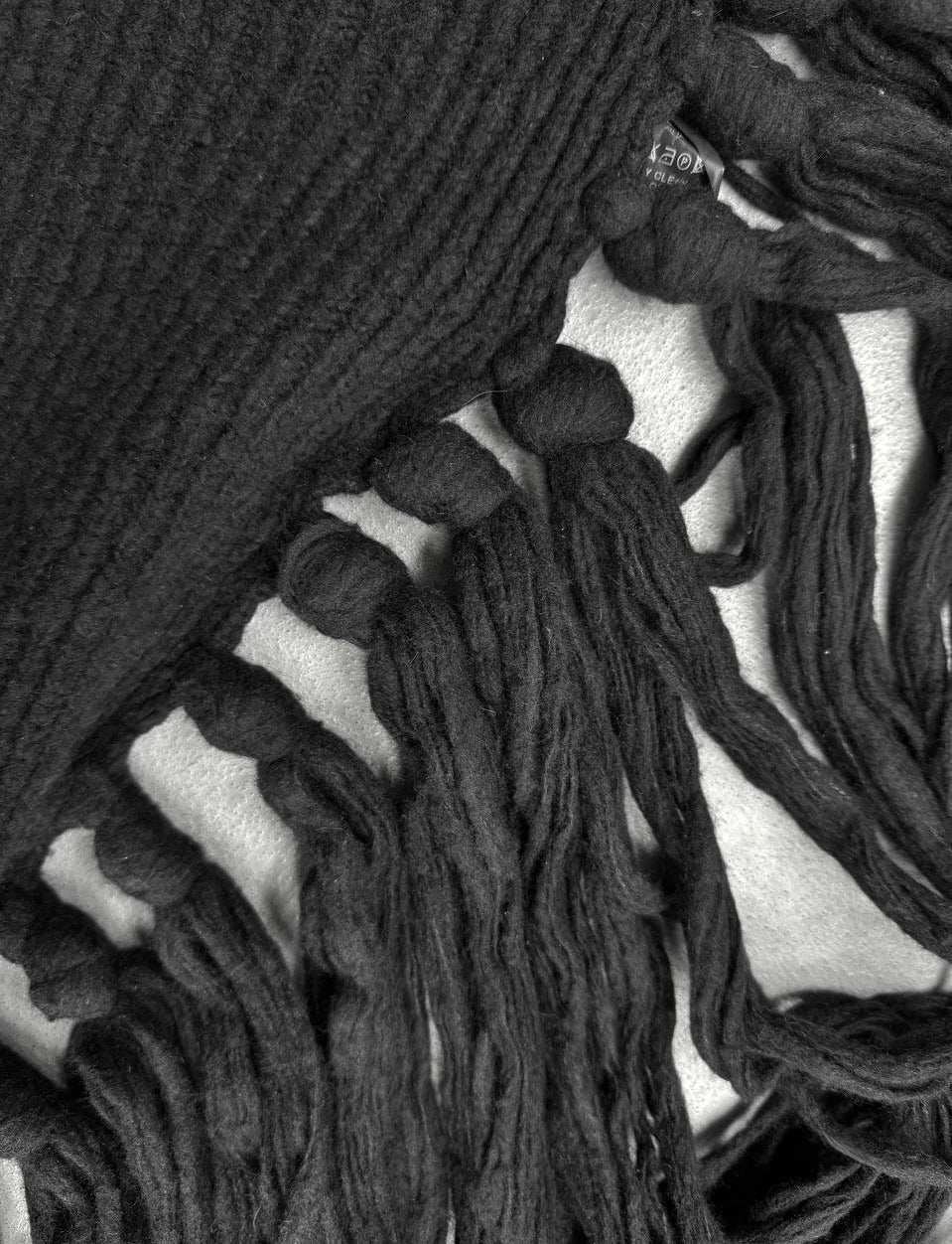 Close-up of a black knitted scarf with tassels on a white background