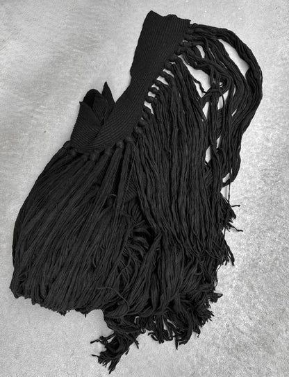 Black knitted scarf with fringe on a gray background