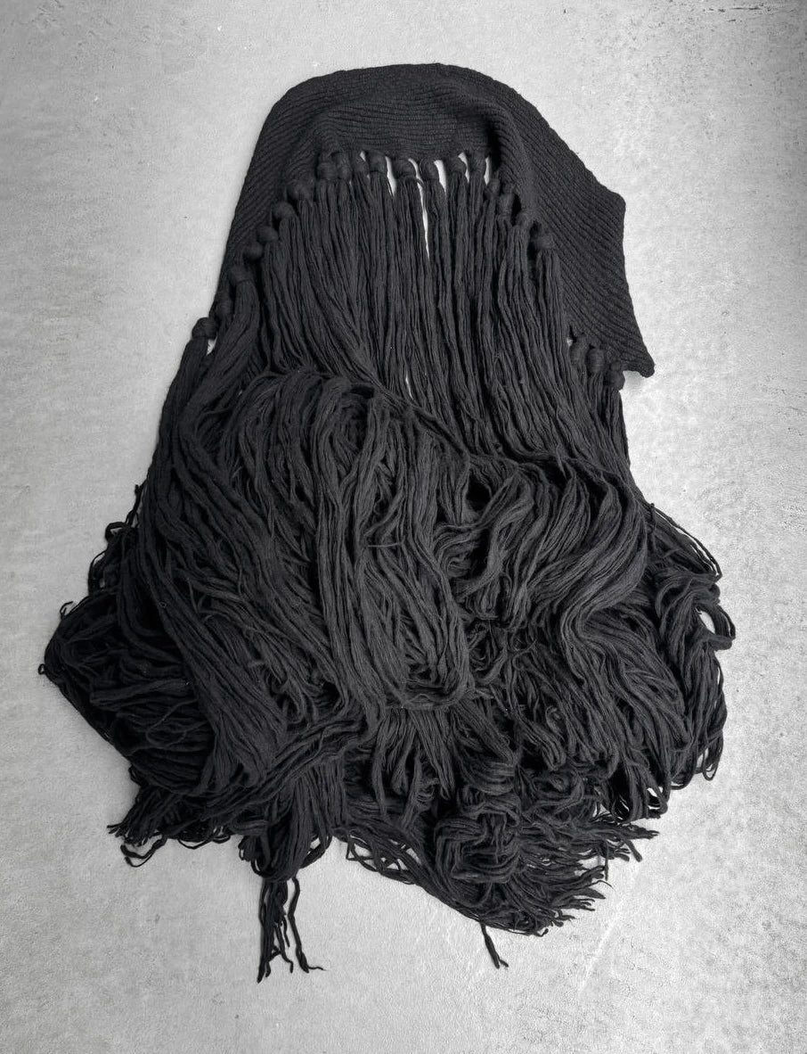 Black knitted scarf with fringe on a gray background