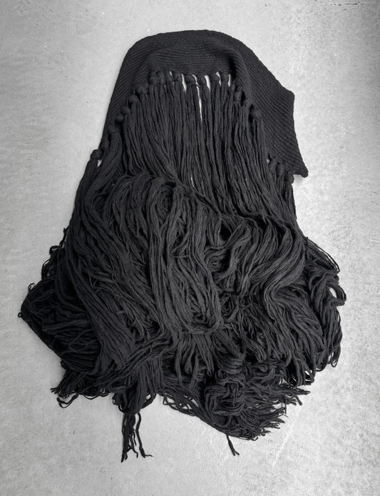 Black knitted scarf with fringe on a gray background