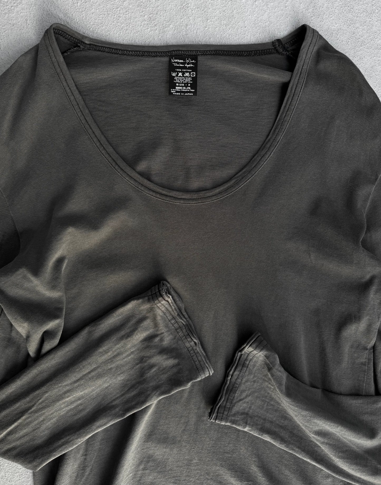 Dark gray long-sleeve shirt with a tag on a light gray background