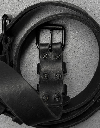 Close-up of a black leather belt with a buckle on a light gray background