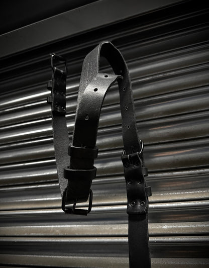 Black leather harness on a corrugated metal background
