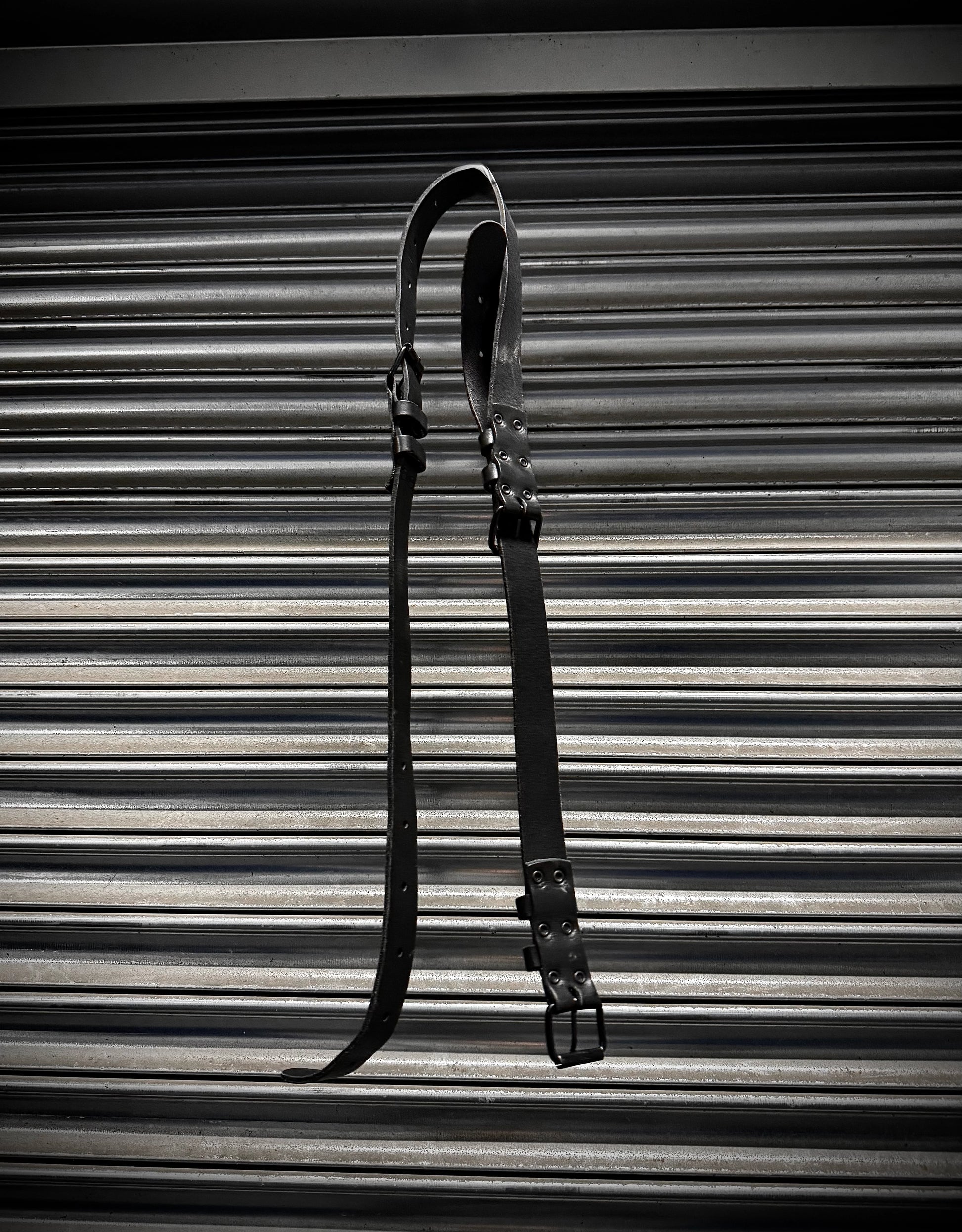 Black leather strap on a corrugated metal background