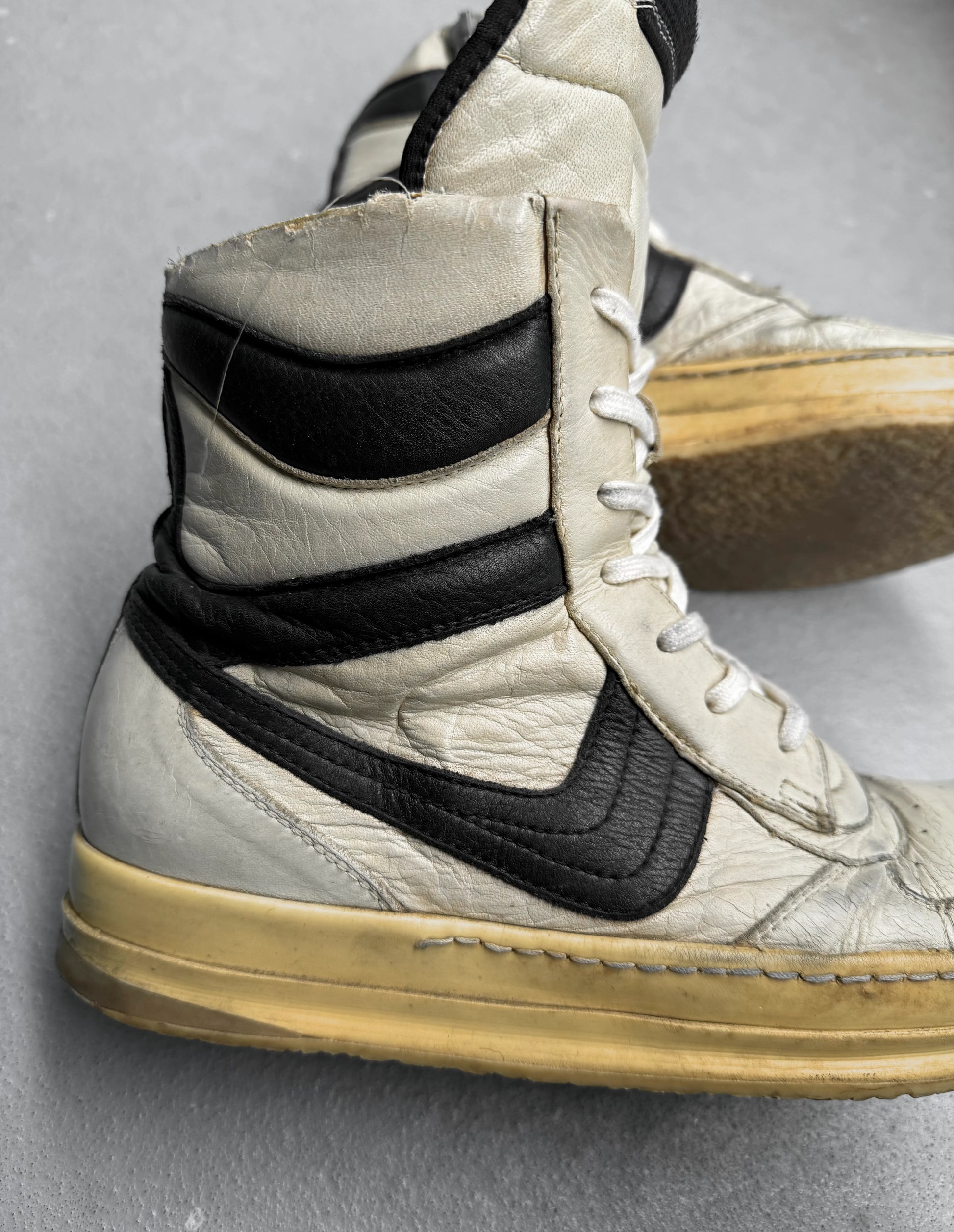 White high-top sneakers with black swoosh logo on a gray background