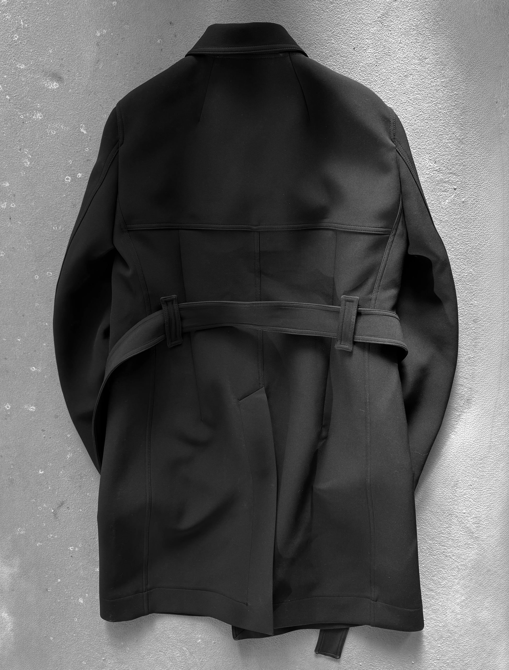 Black trench coat on a textured gray background