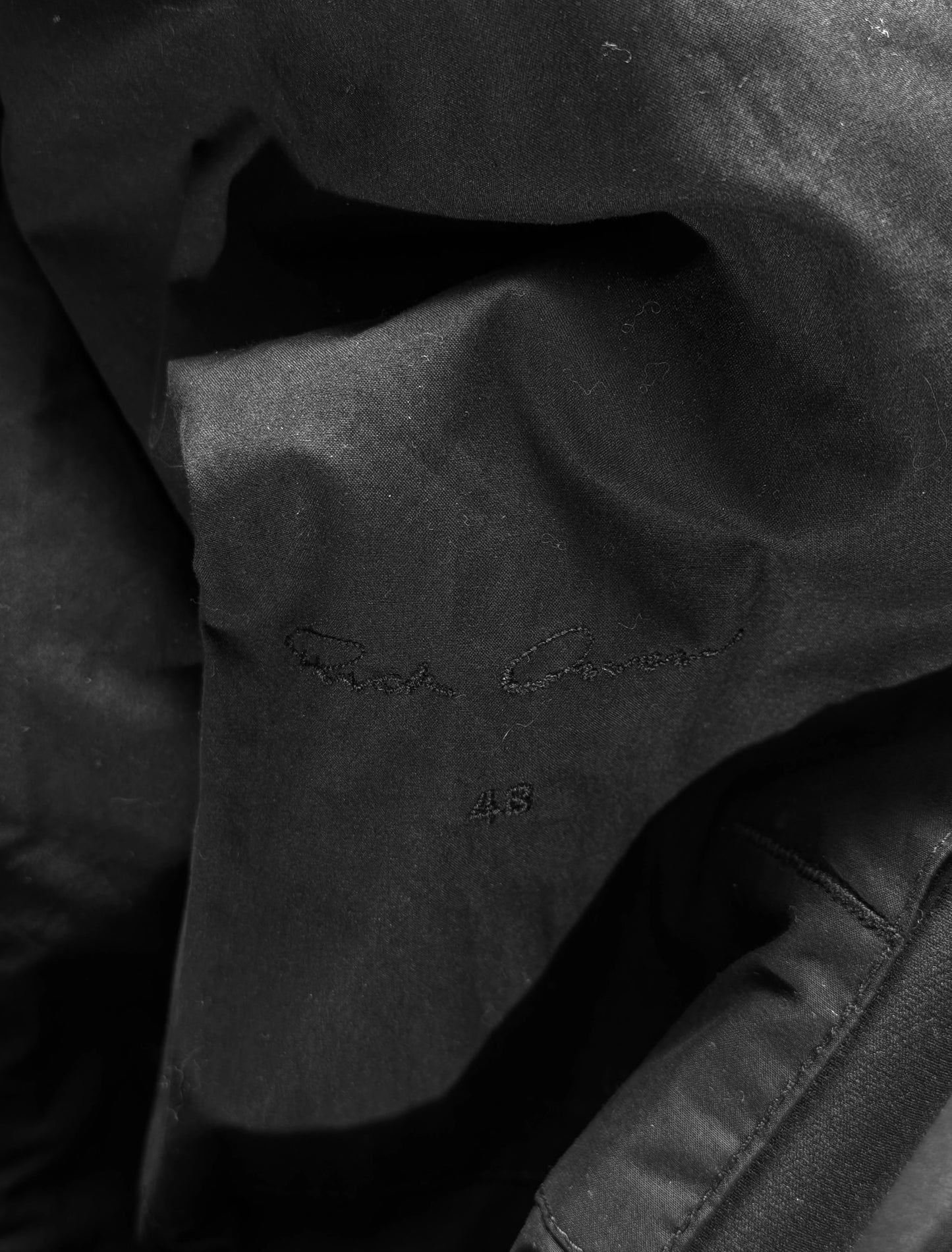 Close-up of black fabric with a brand logo on a dark background