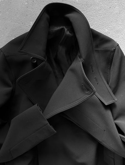 Close-up of a black coat with a textured surface on a gray background