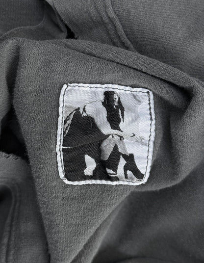 Patch on a dark fabric with a black and white design of a person holding a spear.