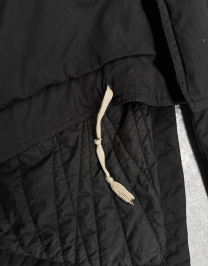 Close-up of a black quilted jacket with a drawstring on a light gray background
