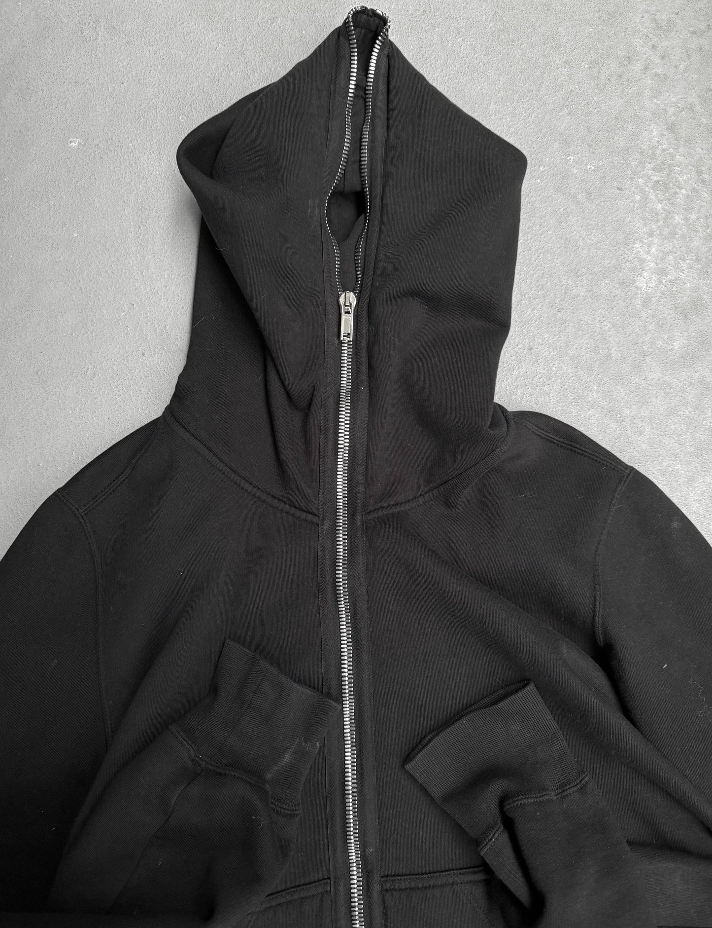 Black hoodie with a zipper on a gray background