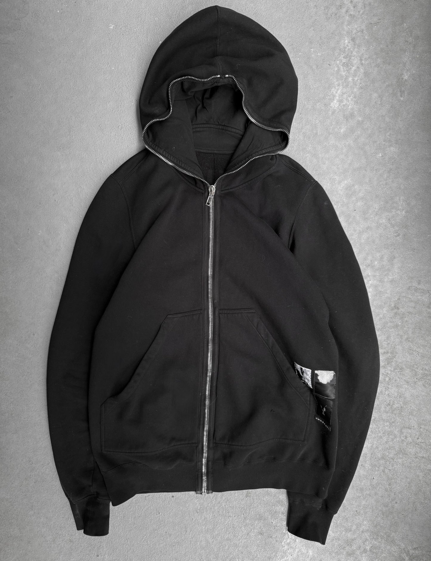 Black hoodie with a zipper on a gray background