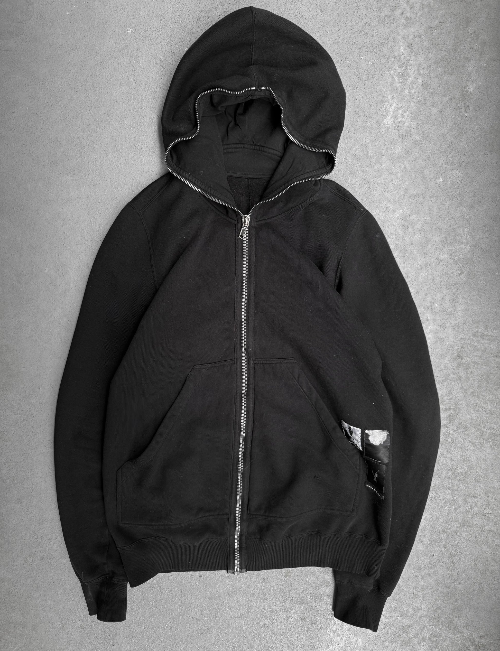 Black hoodie with a zipper on a gray background