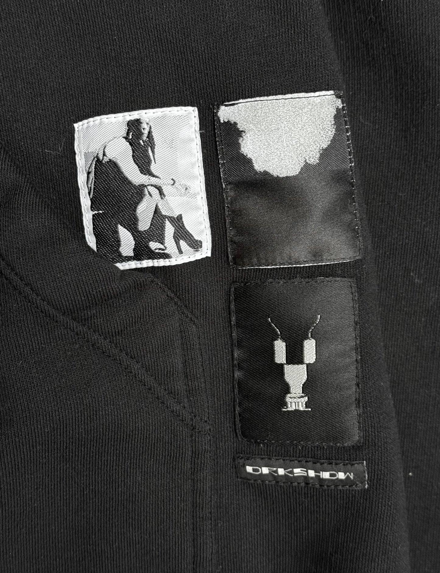 Black jacket with patches featuring a person and a necklace design, with 'Rick Owens' branding.