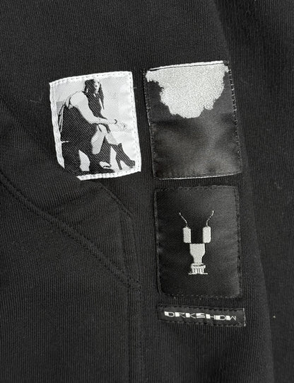 Black jacket with patches featuring a person and a necklace design, with 'Rick Owens' branding.