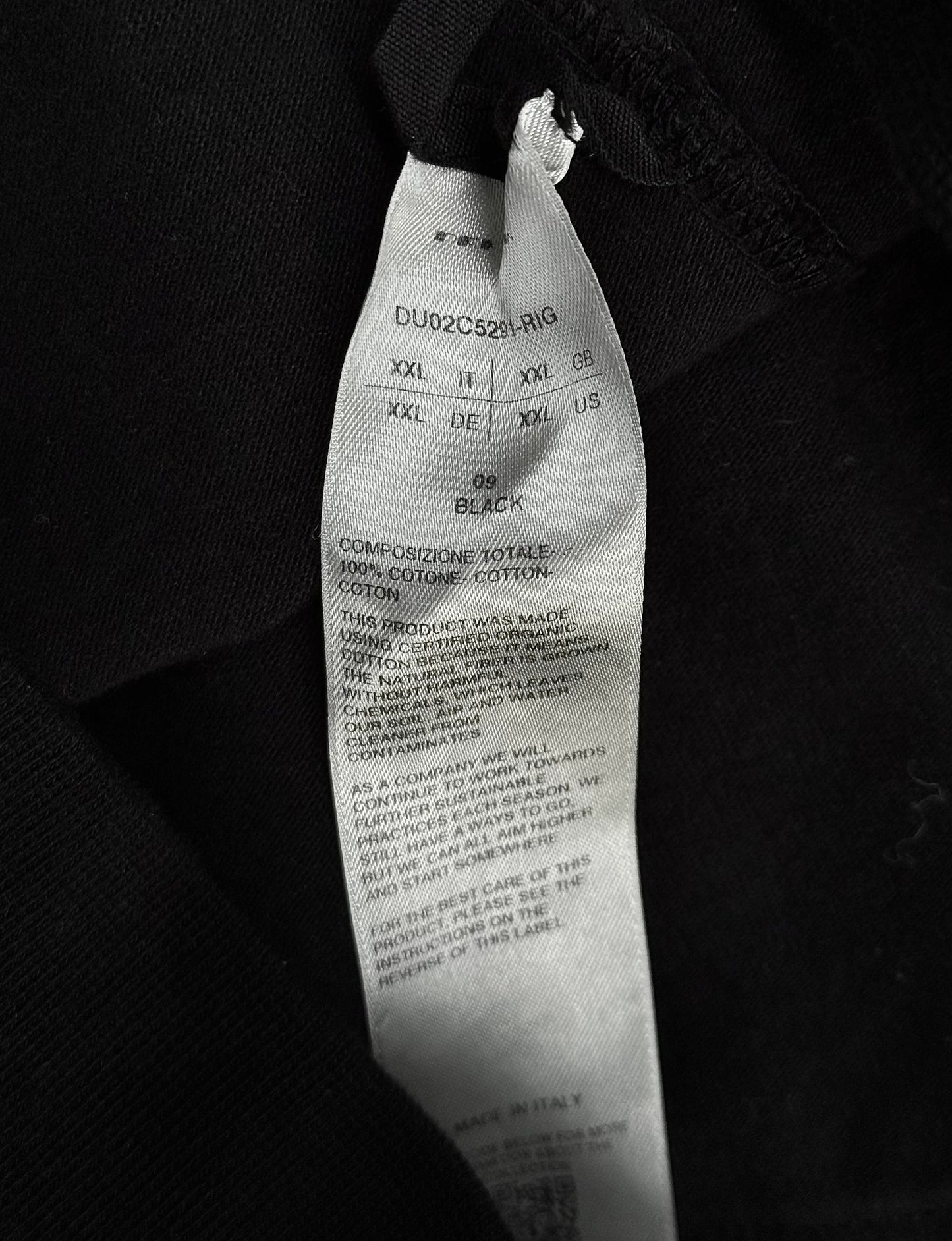 Close-up of a black tie with visible label details on a dark background
