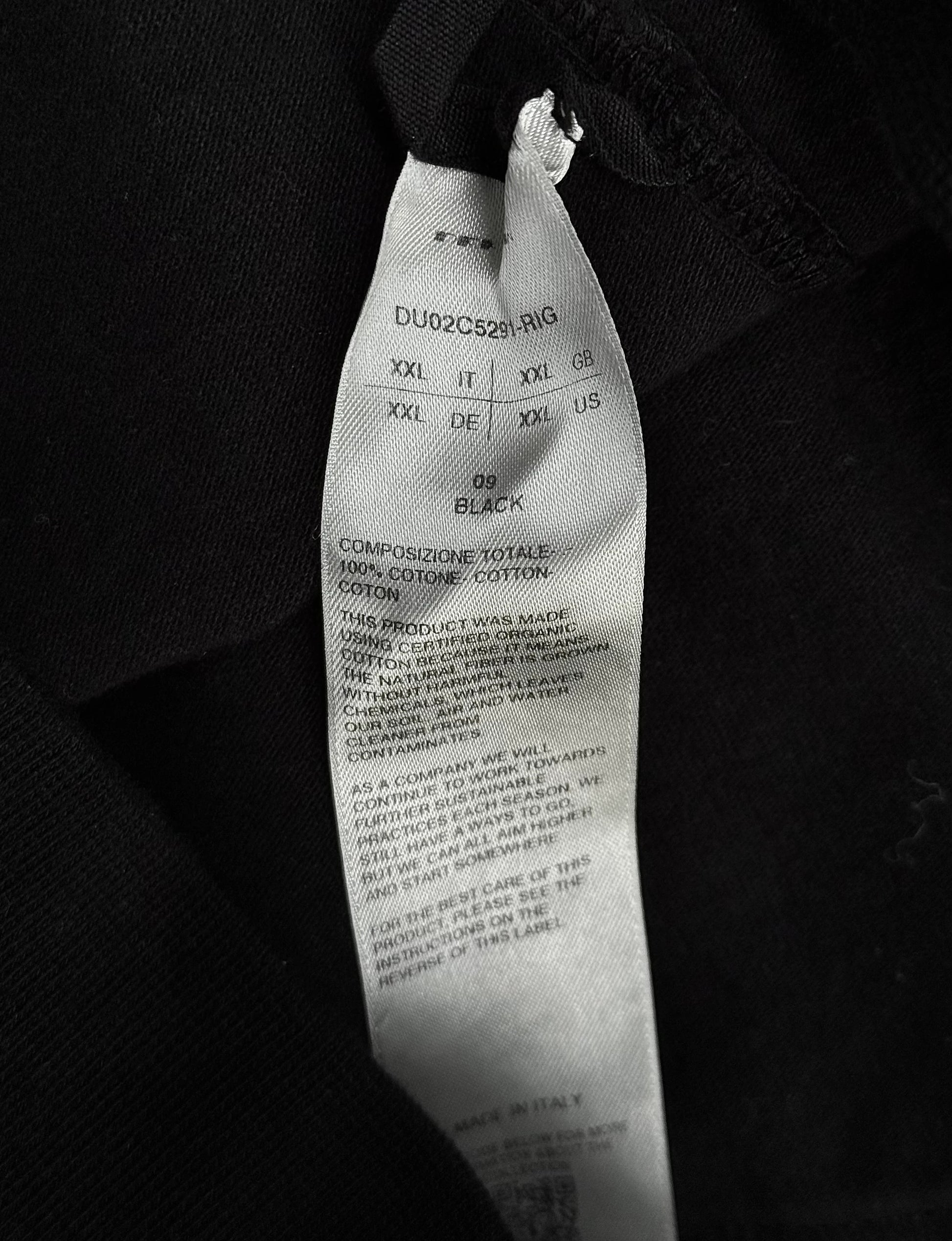 Close-up of a black tie with visible label details on a dark background