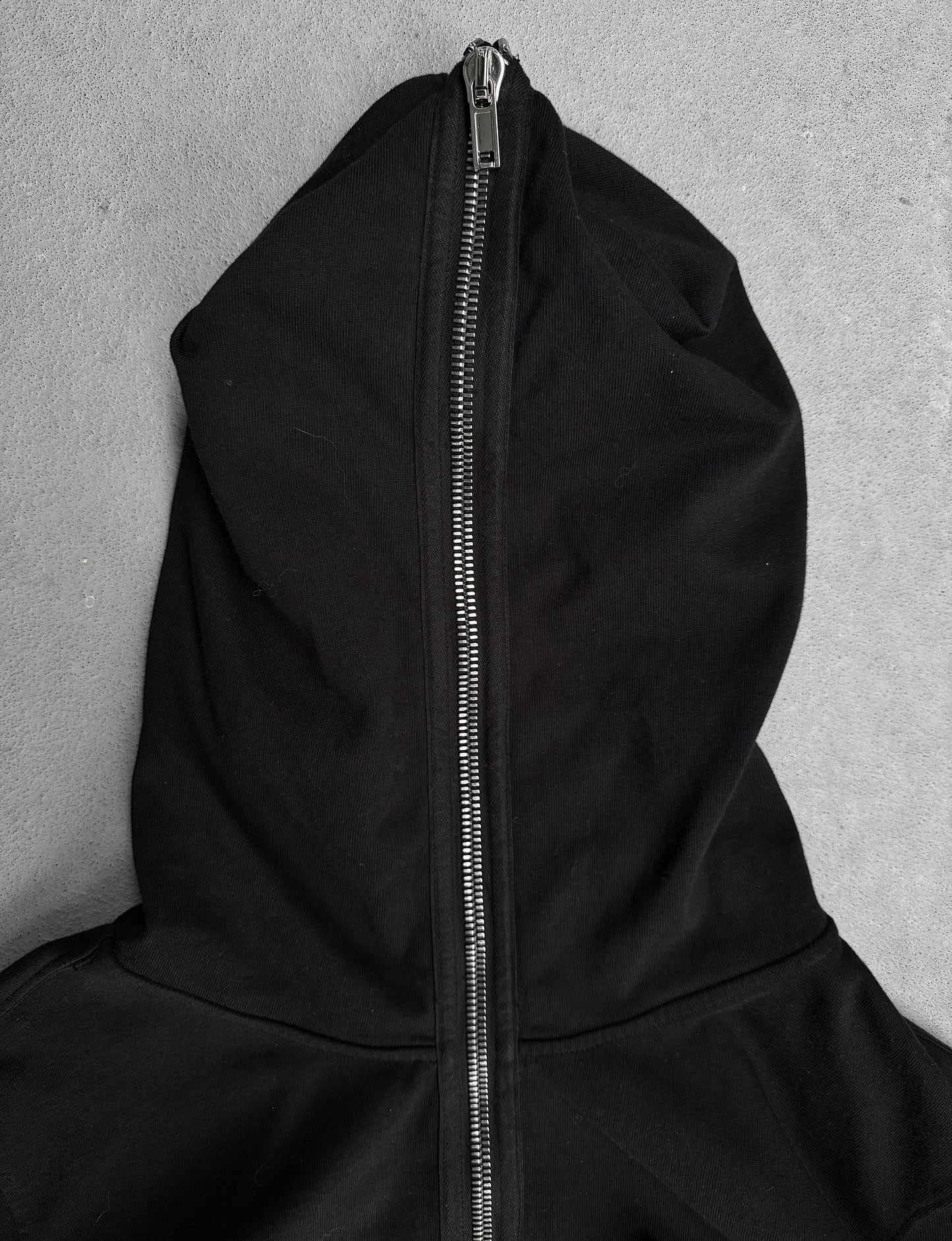 Black hoodie with a zipper on a gray background