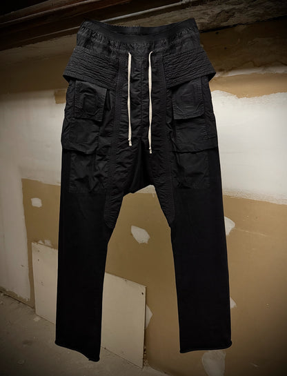 Black cargo pants with multiple pockets and a drawstring on a plain background