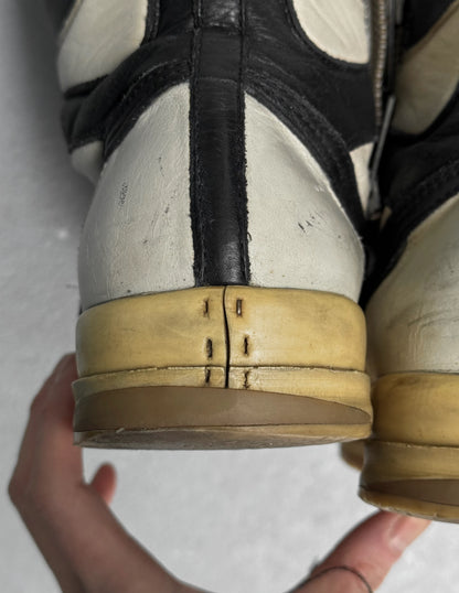 Close-up of a worn shoe with a hand holding it, on a light background