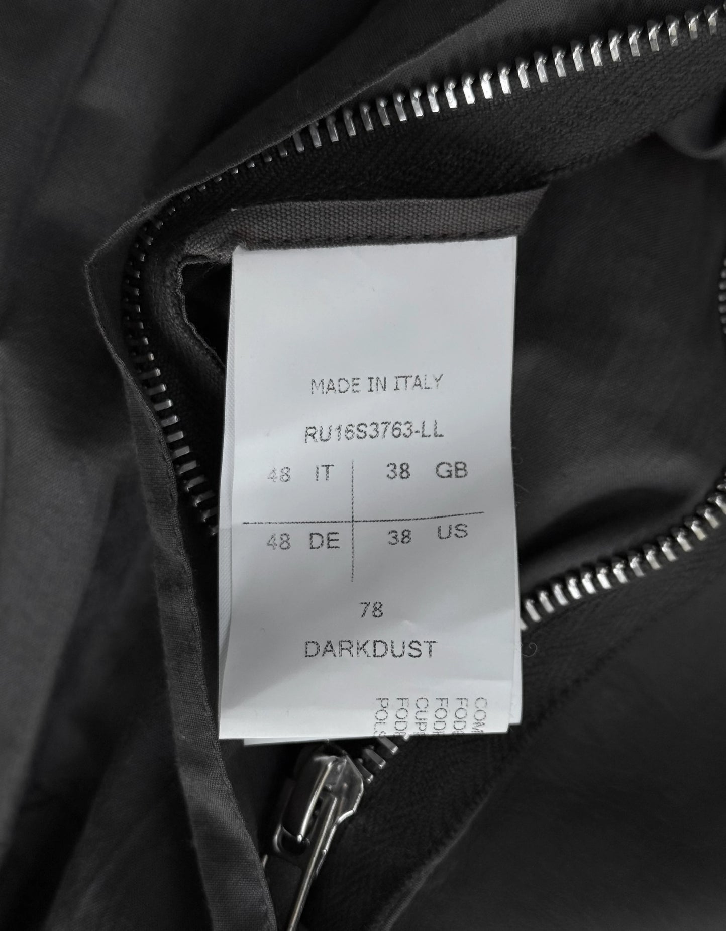 Clothing label on a black jacket with text and size information.