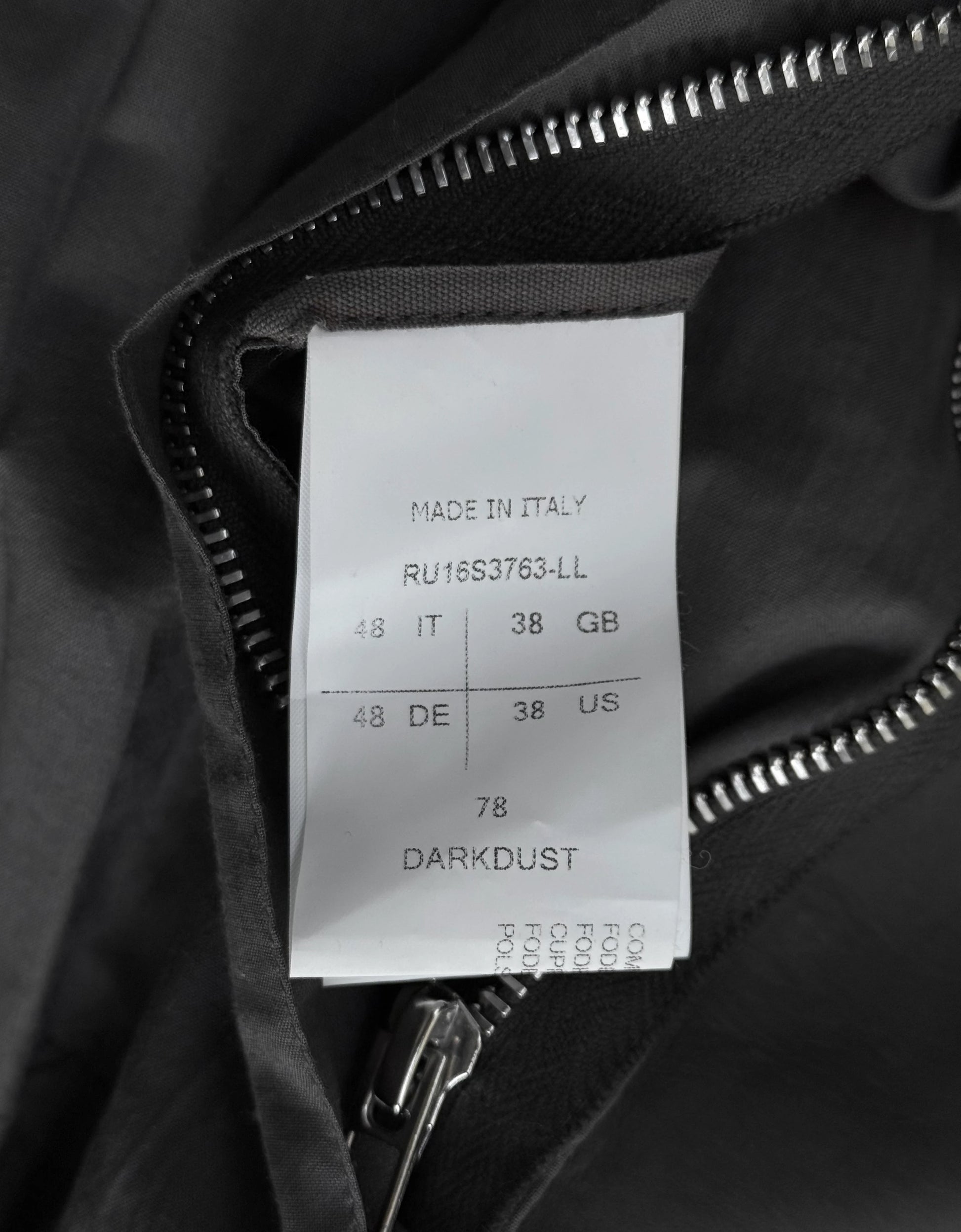 Clothing label on a black jacket with text and size information.