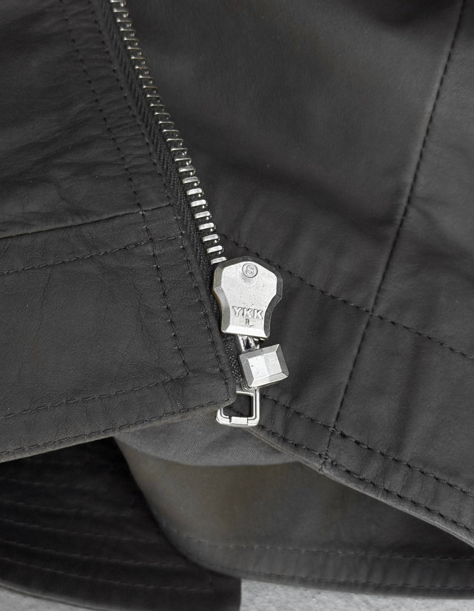 Close-up of a black jacket zipper with a brand logo.