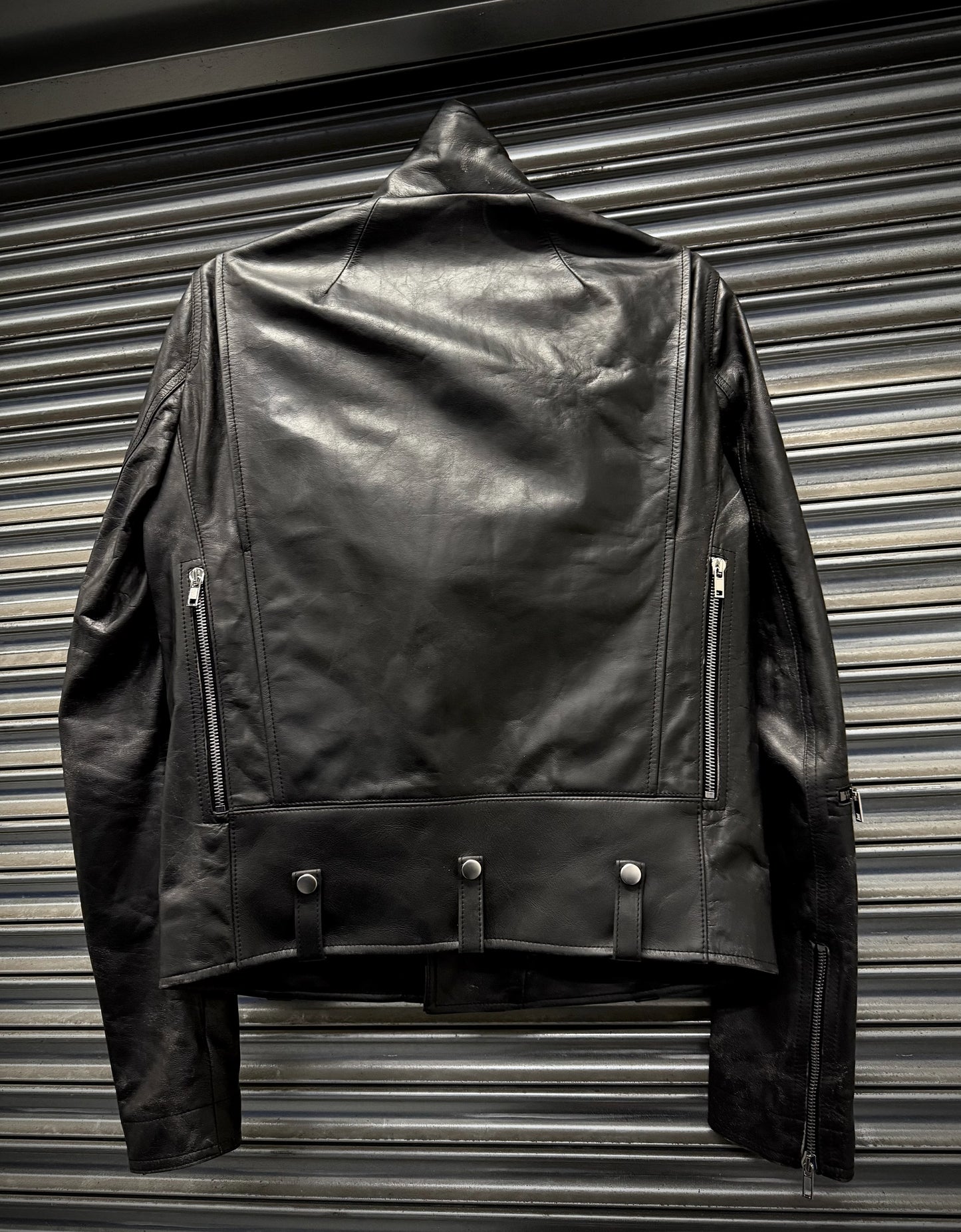Black leather jacket hanging against a metallic background