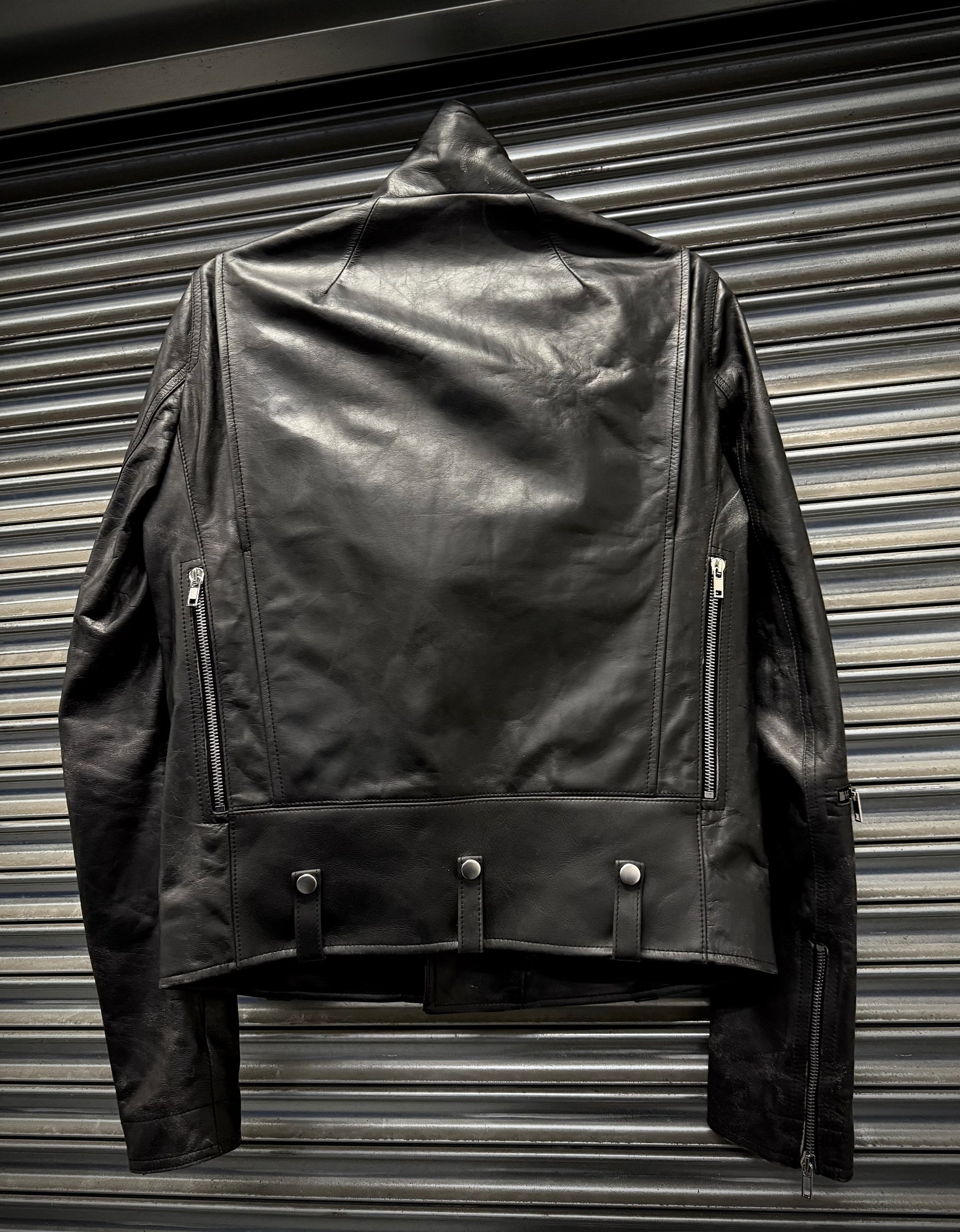 Black leather jacket hanging against a metallic background