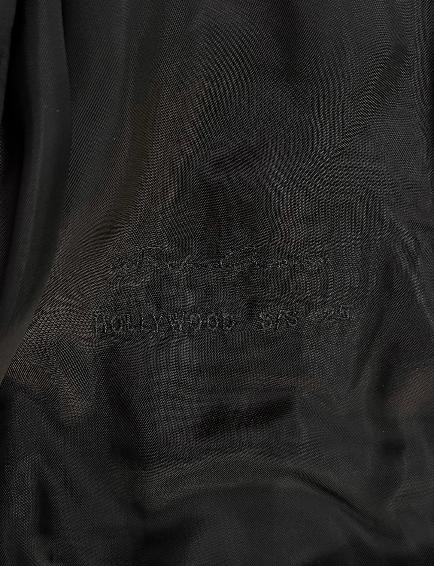 Close-up of black fabric with 'Hollywood S/S 25' embroidery