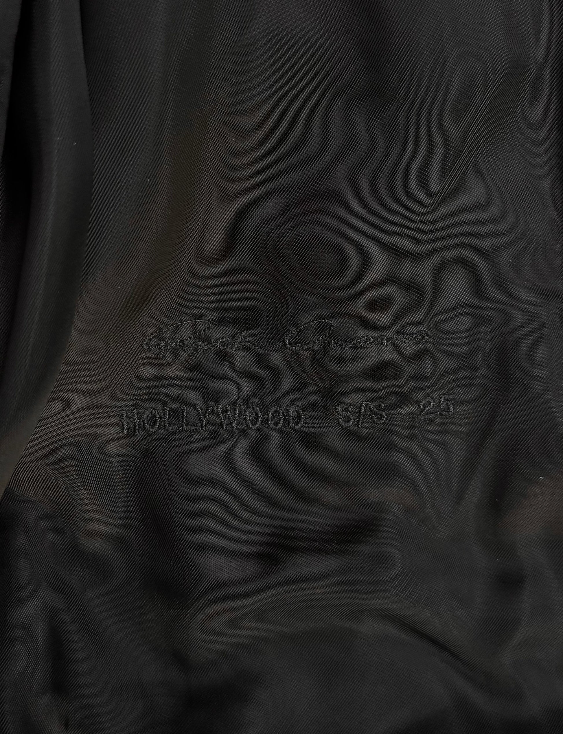 Close-up of black fabric with 'Hollywood S/S 25' embroidery