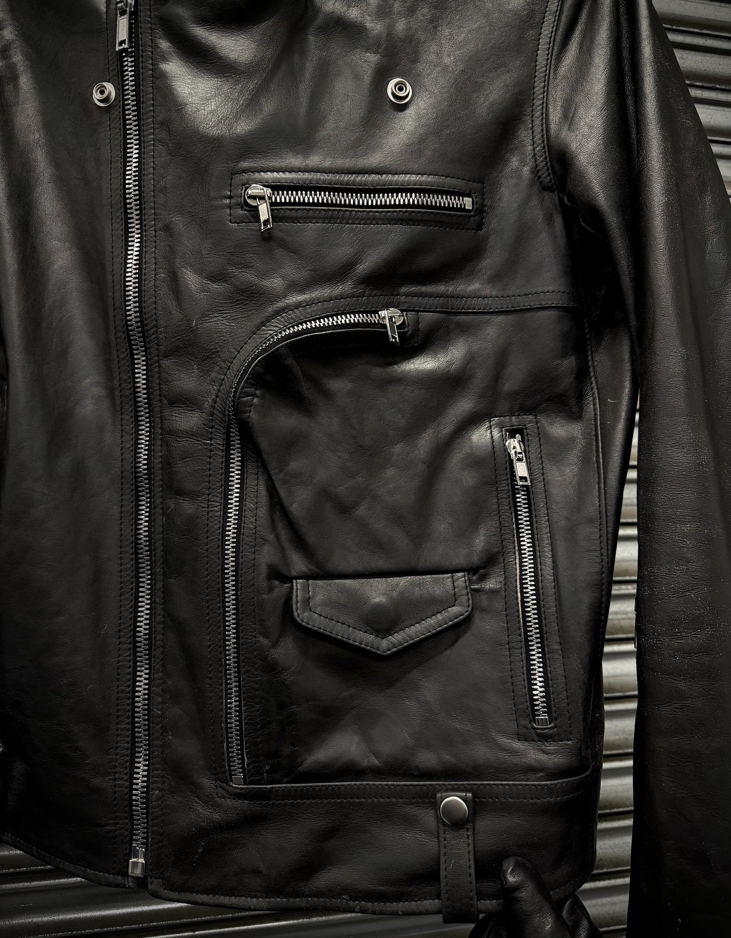 Close-up of a black leather jacket with zippers on a metallic surface