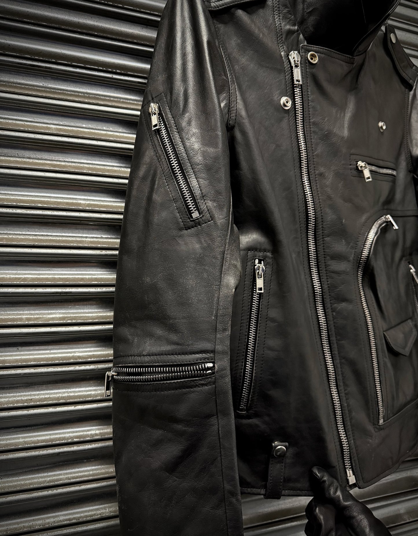 Black leather jacket with multiple zippers against a metallic background