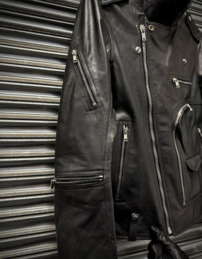 Black leather jacket with multiple zippers against a metallic background