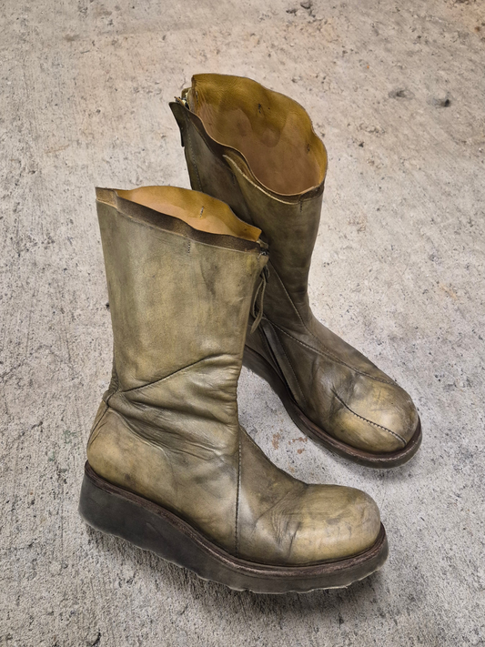 Pair of worn leather boots on a concrete floor