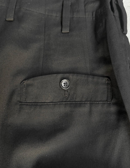 Close-up of dark gray pants with a button on a plain background