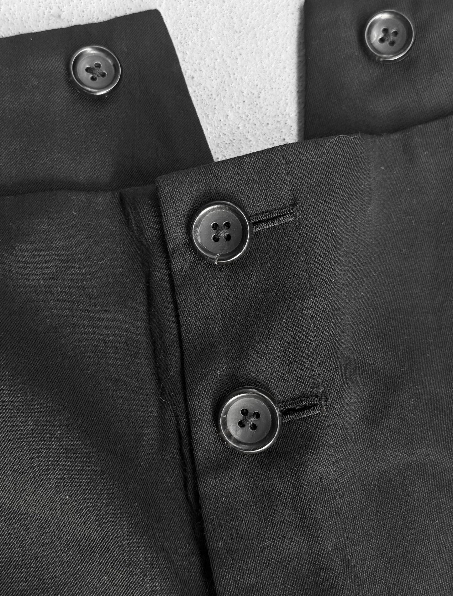 Close-up of a black coat with buttons on a textured surface