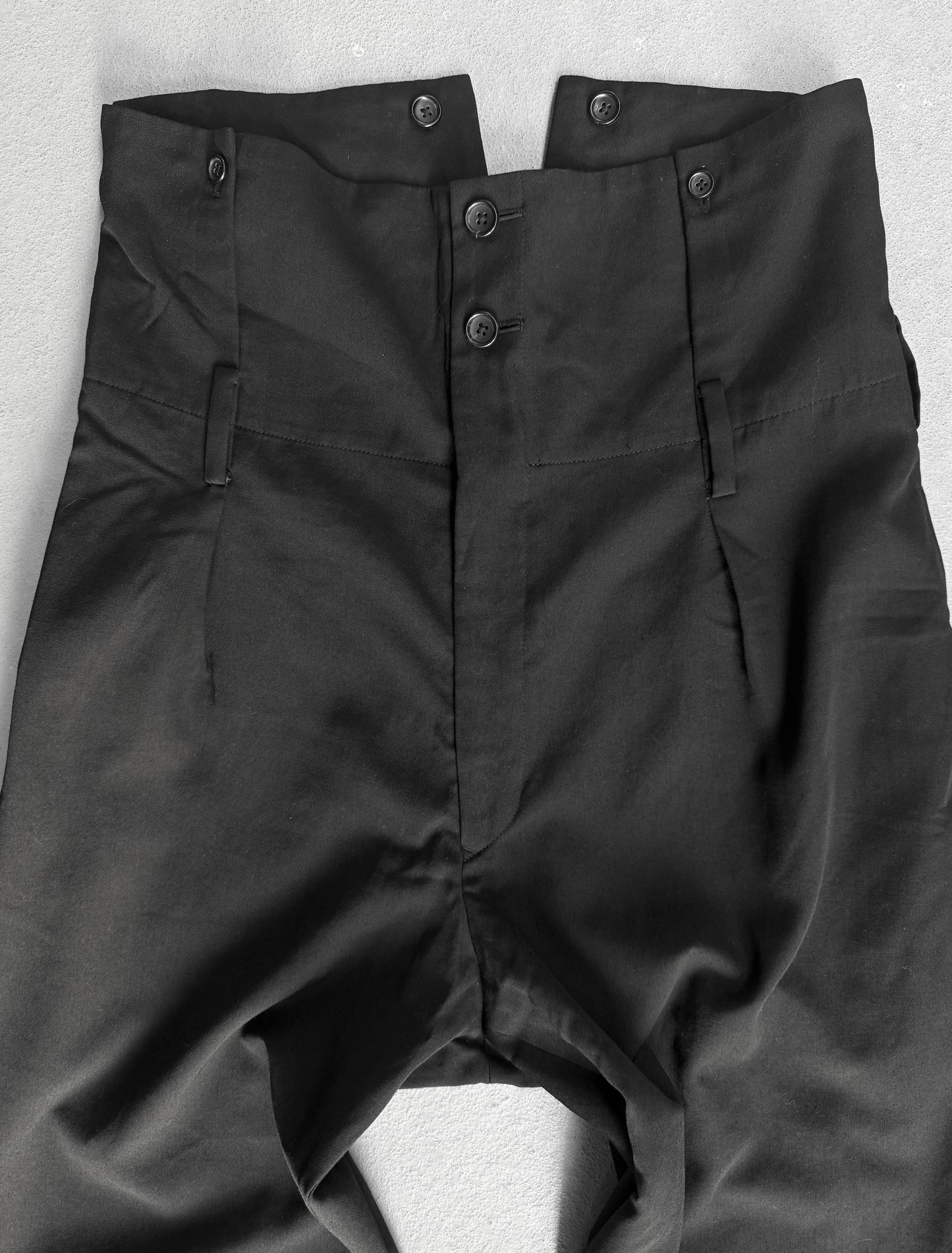 Black pants with buttons on a light gray background