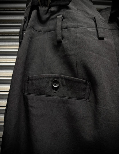 Close-up of a dark coat with a buttoned pocket against a metallic background