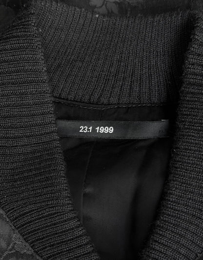 Close-up of a textured black garment with a label showing '23.1 1999'.
